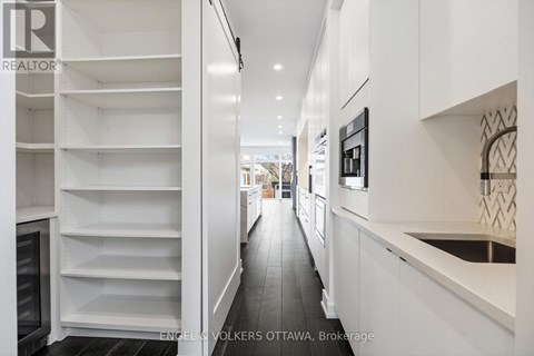A modern kitchen with white cabinets and a black refrigerator.