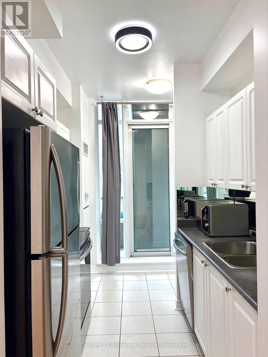 A modern kitchen with white cabinets and a stainless steel refrigerator.