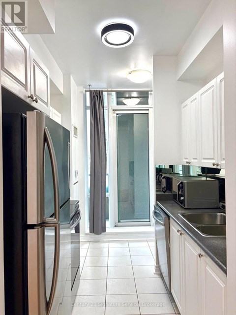 A modern kitchen with white cabinets and a stainless steel refrigerator.