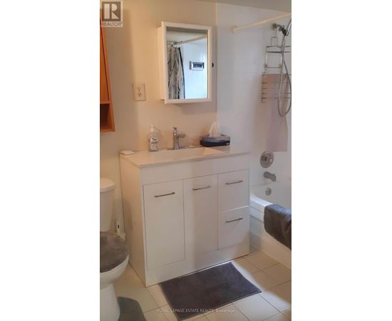 A white bathroom with a toilet, sink, and mirror.