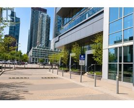 A building with a glass facade is surrounded by a metal fence and a sign that reads "RE/MAX HALLMARK REALTY LTD. Brokerage".