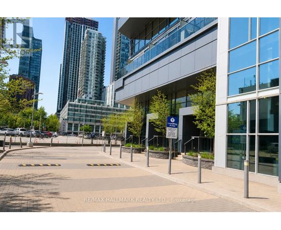 A building with a glass facade is surrounded by a metal fence and a sign that reads "RE/MAX HALLMARK REALTY LTD. Brokerage".