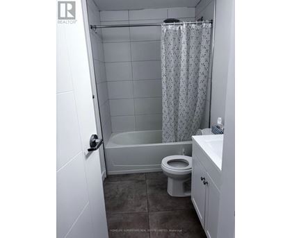 A white bathroom with a toilet, sink, and shower.