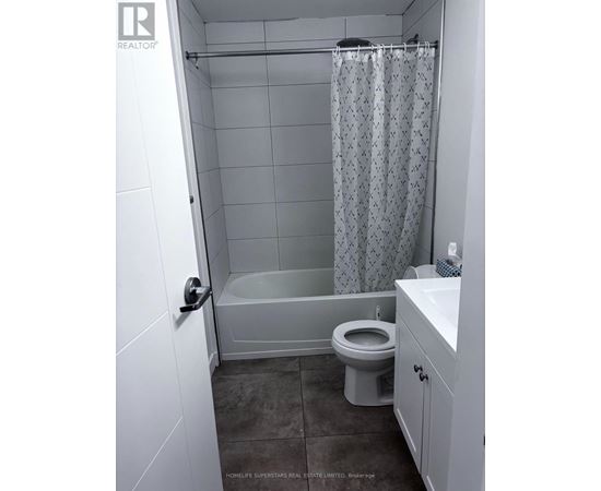 A white bathroom with a toilet, sink, and shower.