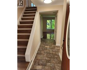 A hallway with a staircase and a tiled floor.
