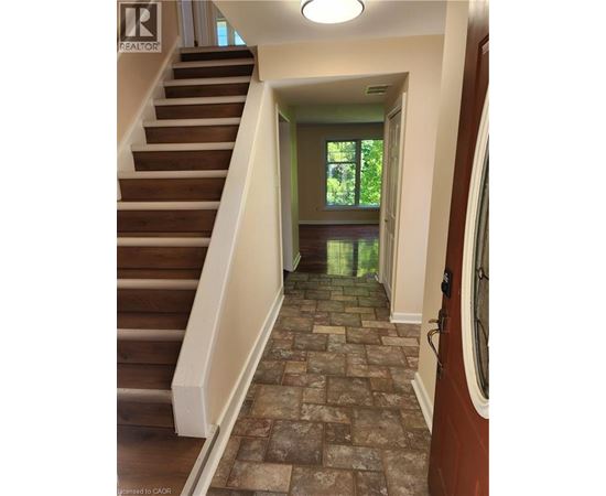 A hallway with a staircase and a tiled floor.