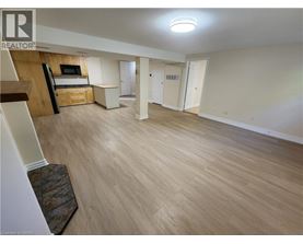 A spacious living room with light wood flooring and a television.