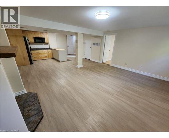 A spacious living room with light wood flooring and a television.