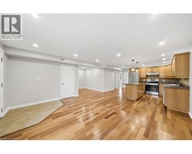 A spacious room with wooden flooring and a kitchen area.