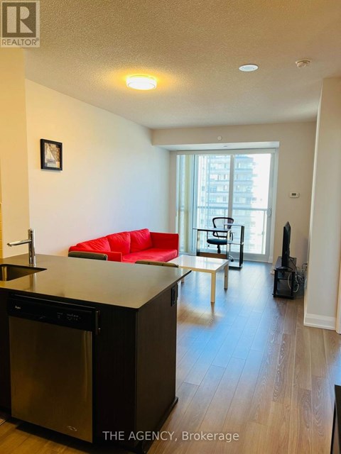 A kitchen with a red couch in the living room.