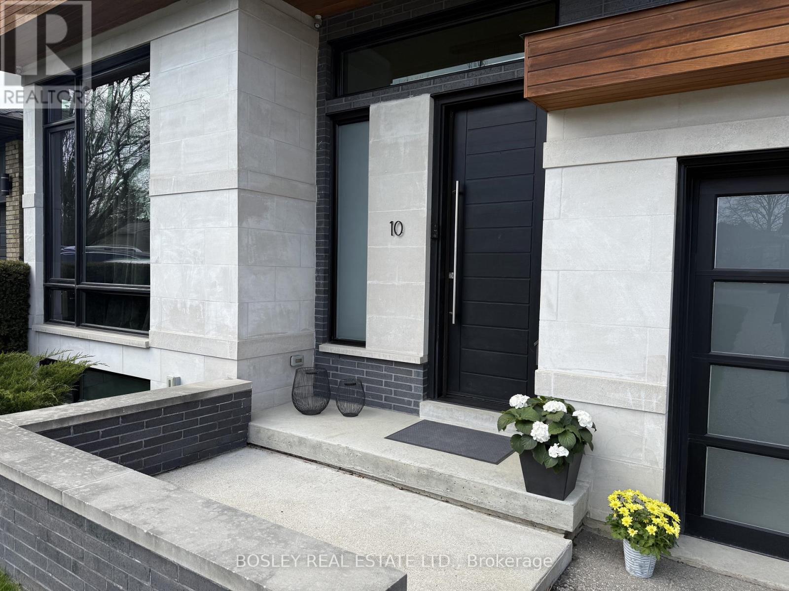 A modern house entrance with a black door and steps leading up to it.