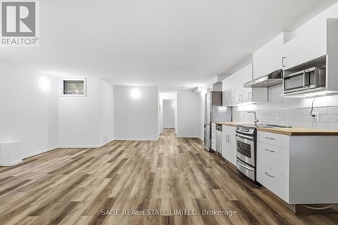 A spacious kitchen with white cabinets and a wooden floor.