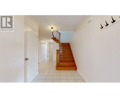 A white hallway with a wooden staircase and a white door.