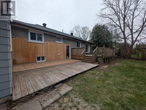 A wooden deck is in front of a grey house.