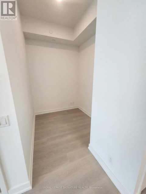 A white hallway with a wooden floor and white walls.