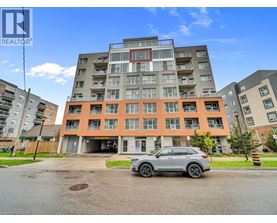 A grey car is parked in front of a multi-story apartment building.