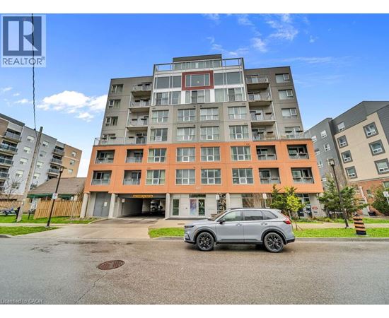A grey car is parked in front of a multi-story apartment building.