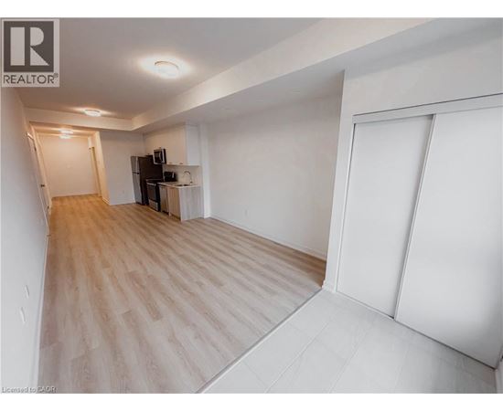 A spacious room with wooden flooring and white walls.