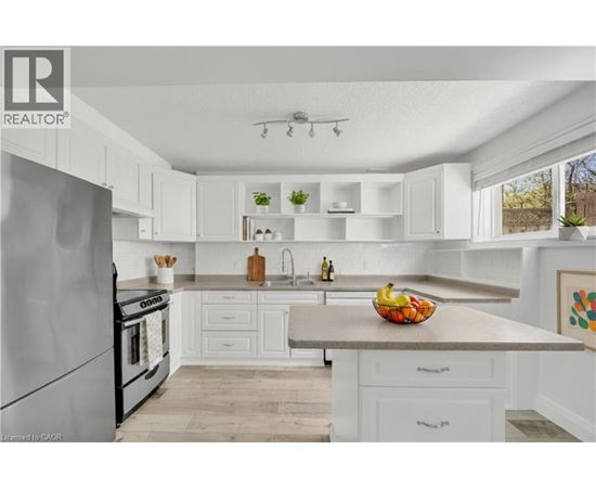 A modern kitchen with white cabinets and a stainless steel refrigerator.