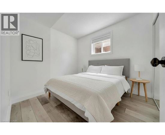 A bedroom with a bed, a small table, and a framed picture on the wall.