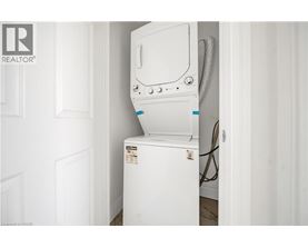 A white dishwasher is installed in a narrow space between a door and a wall.