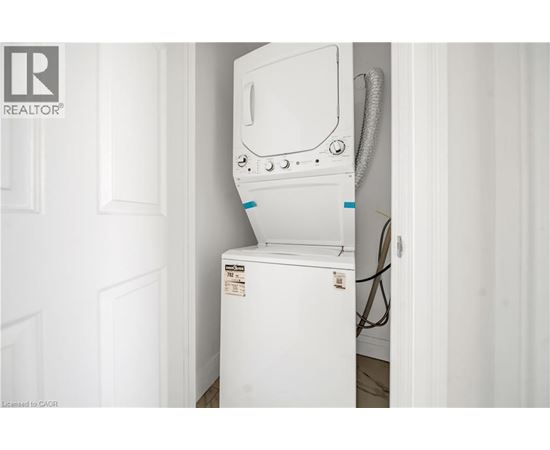 A white dishwasher is installed in a narrow space between a door and a wall.