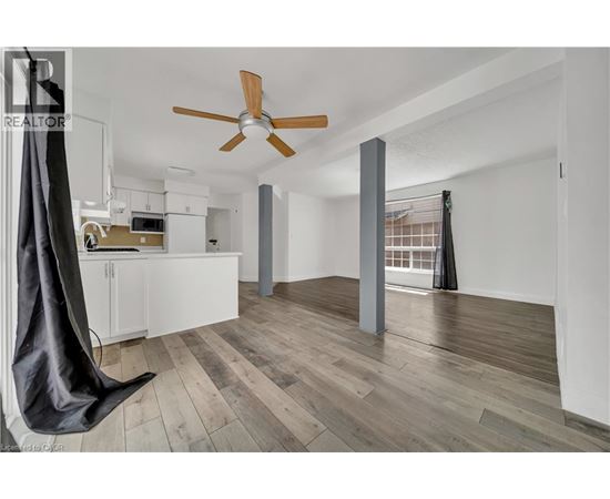 A modern kitchen with a hanging chair and a ceiling fan.