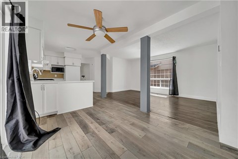 A modern kitchen with a hanging chair and a ceiling fan.