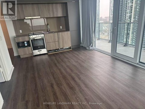 A kitchen area with wooden flooring and a large window.