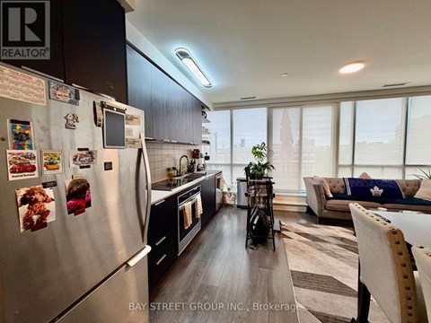 A modern kitchen with a refrigerator covered in magnets and a dining area with a striped rug.