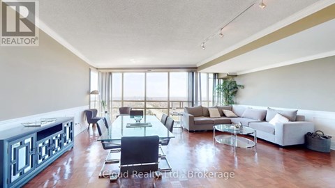 A spacious living room with a dining table and chairs, a sofa set, and a large window with a view of the outdoors.