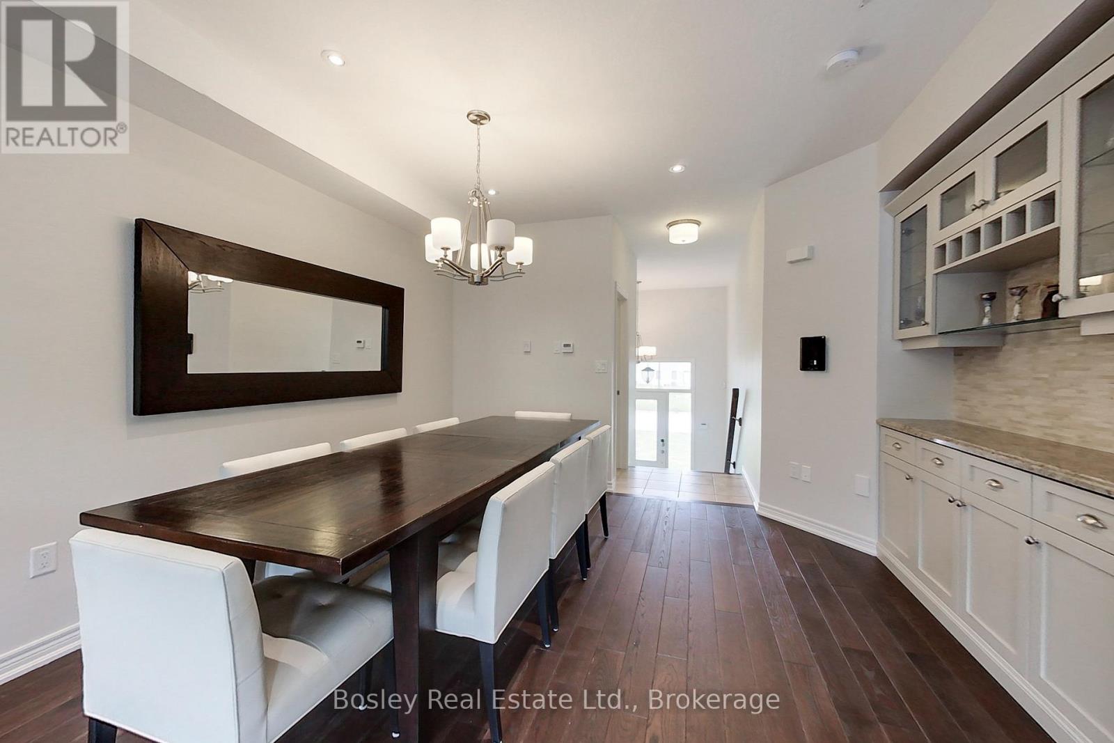 A dining room with a wooden table and white chairs.
