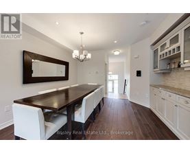A dining room with a wooden table and white chairs.