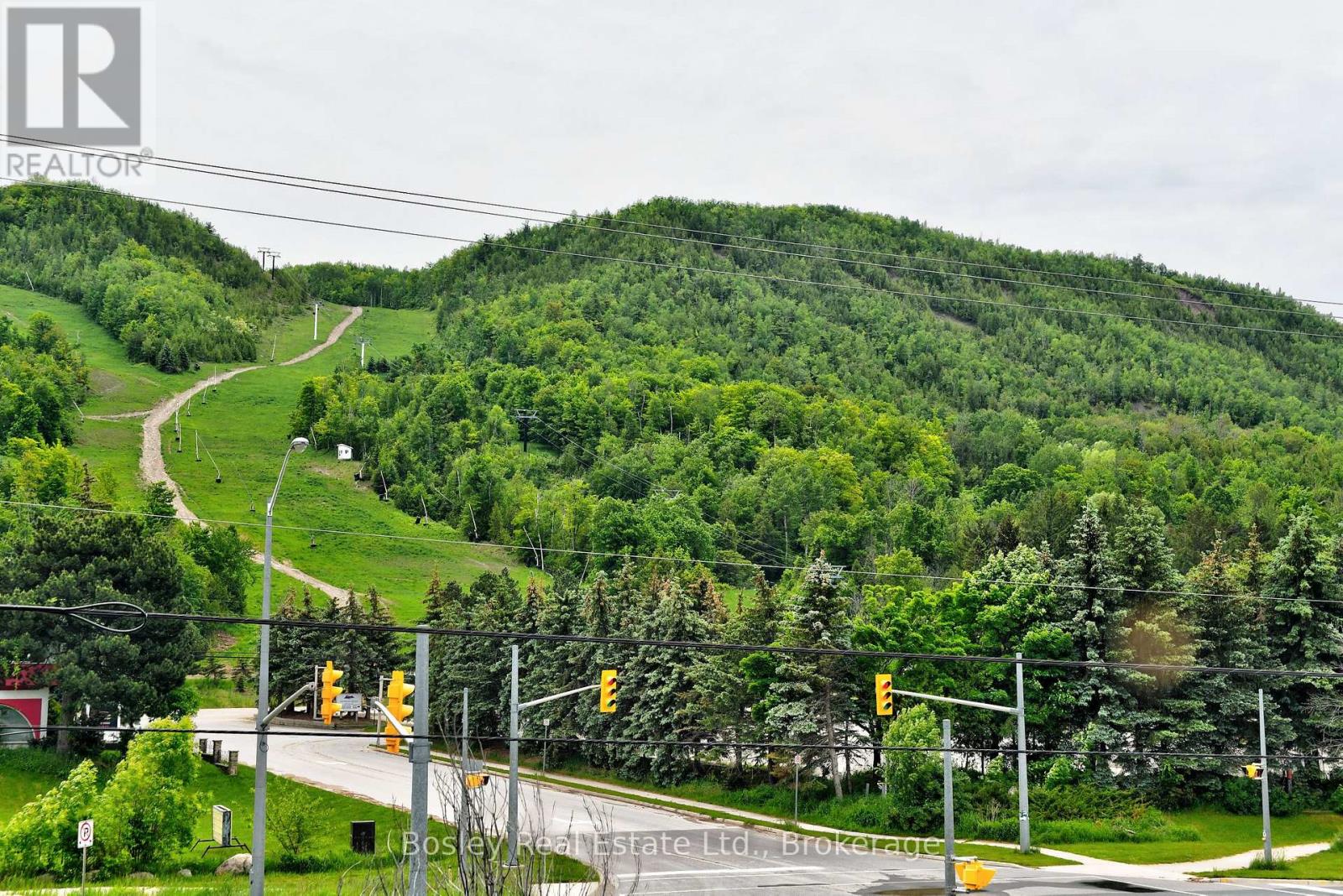 A road with traffic lights and a hill with trees in the background.