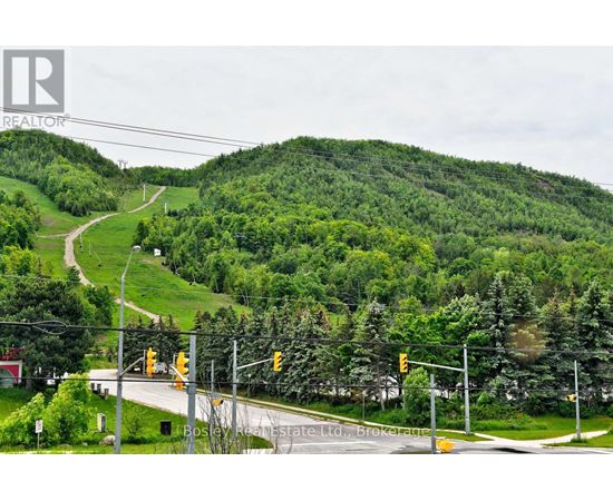 A road with traffic lights and a hill with trees in the background.
