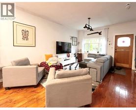 A living room with a grey couch, a chair, a sofa, a television, and a window.