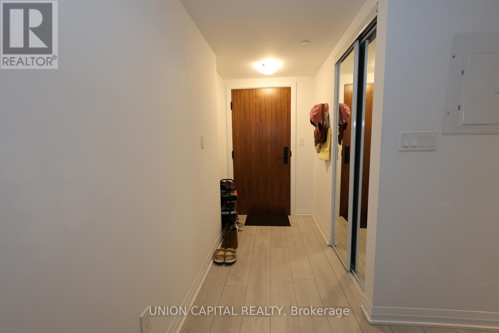 A hallway with a wooden door and a pair of shoes on the floor.