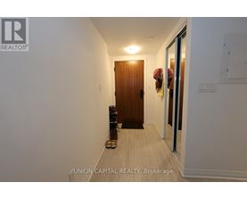 A hallway with a wooden door and a pair of shoes on the floor.