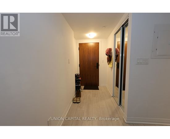 A hallway with a wooden door and a pair of shoes on the floor.