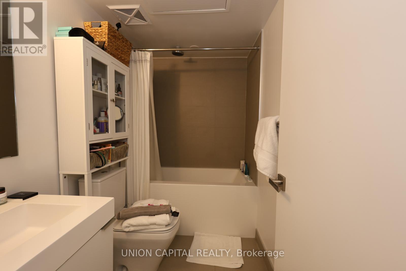 A bathroom with a white sink and a white cabinet with a mirror above it.