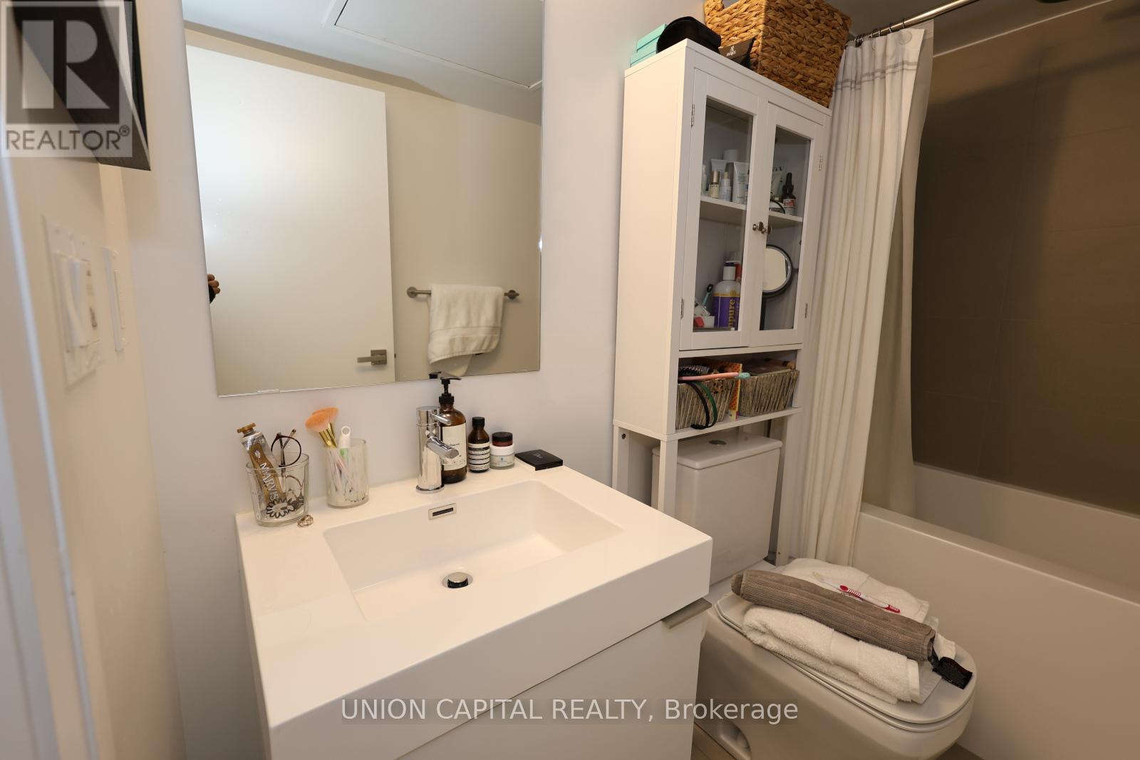 A bathroom with a sink, mirror, and cabinet.
