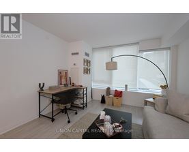 A well-lit, modern living room with a couch, chair, and desk.
