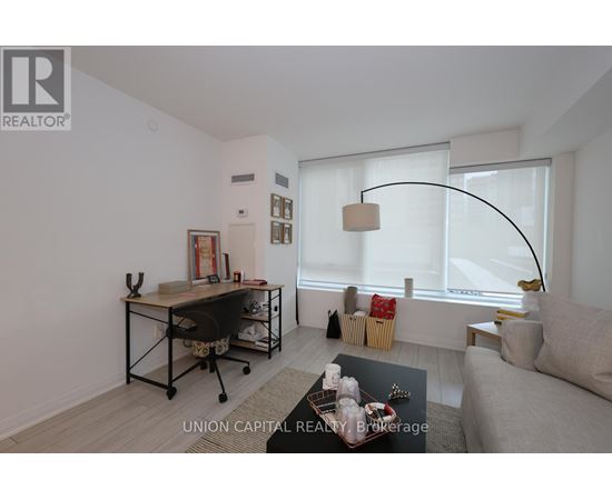 A well-lit, modern living room with a couch, chair, and desk.