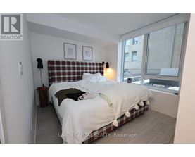 A bedroom with a bed, pillows, and a window.