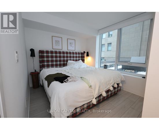 A bedroom with a bed, pillows, and a window.