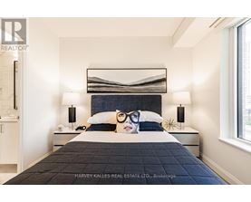 A bedroom with a large bed and a painting of a woman's face on the pillow.