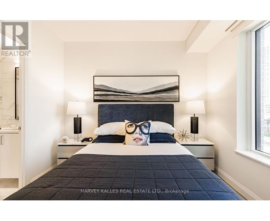 A bedroom with a large bed and a painting of a woman's face on the pillow.