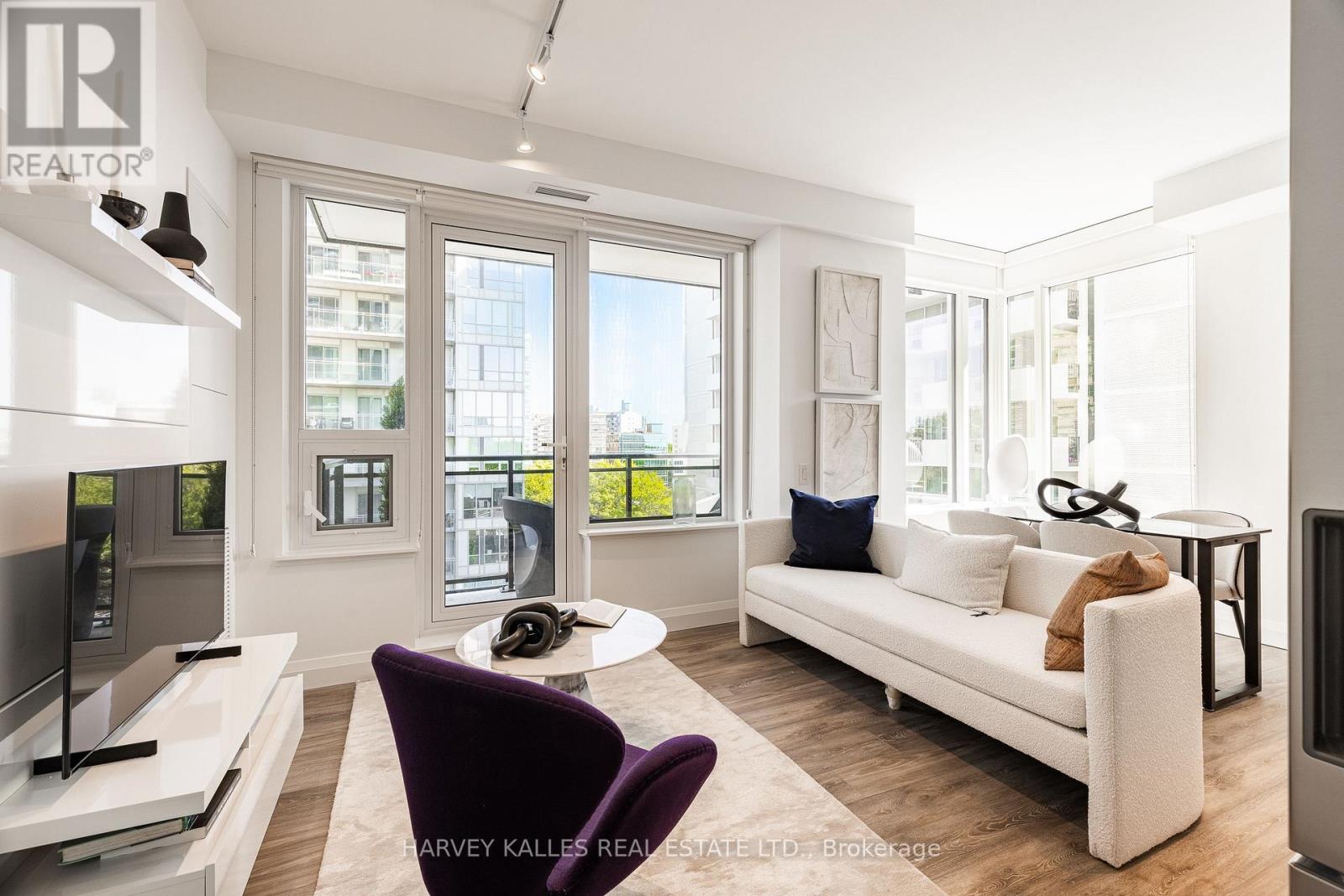 A living room with a purple chair and a white couch.