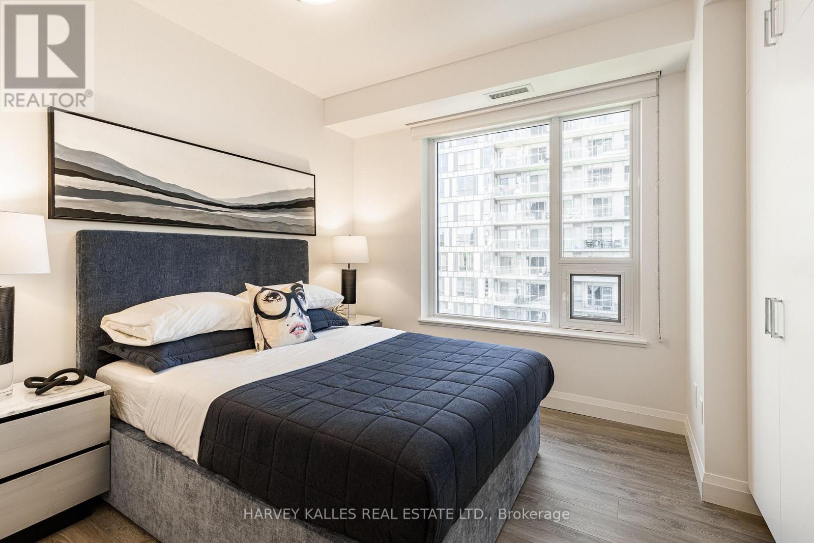A bedroom with a large bed and a window overlooking a cityscape.