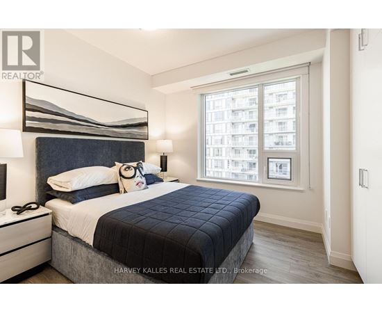 A bedroom with a large bed and a window overlooking a cityscape.